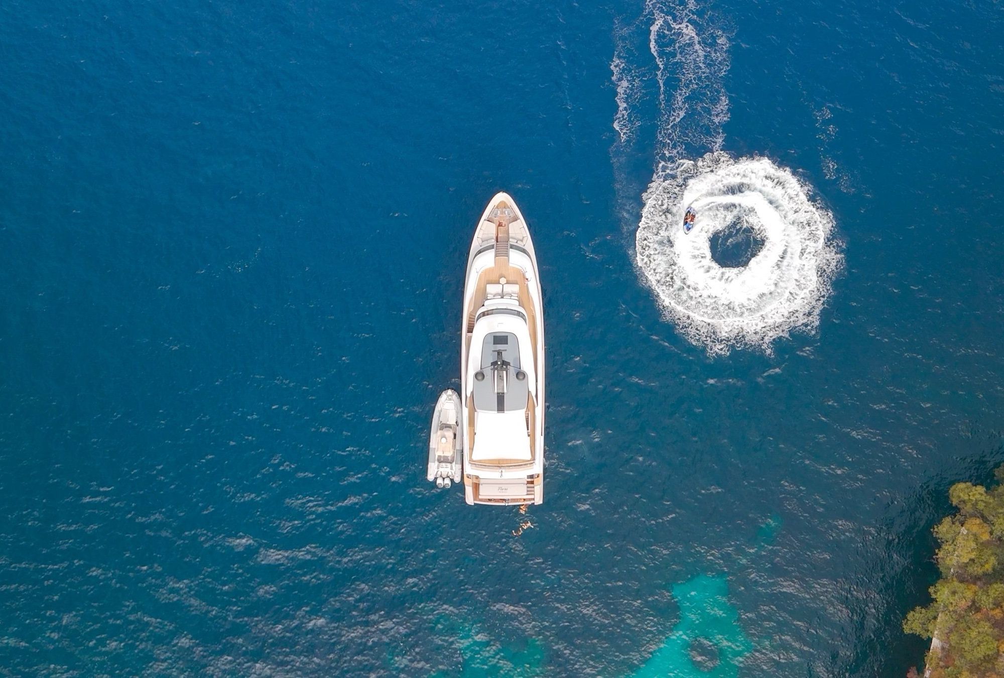 FLORI from above, at anchor in turquoise water with a jet ski alongside